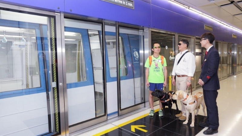 主人及导盲犬等候登无人驾驶列车。