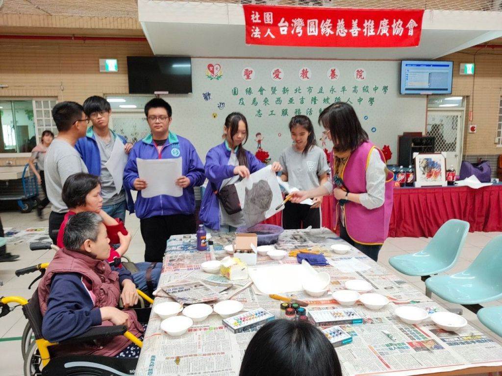 老憨兒院生認真眼神看著玉嬋理事長與高中生一起討論如何無筆彩繪